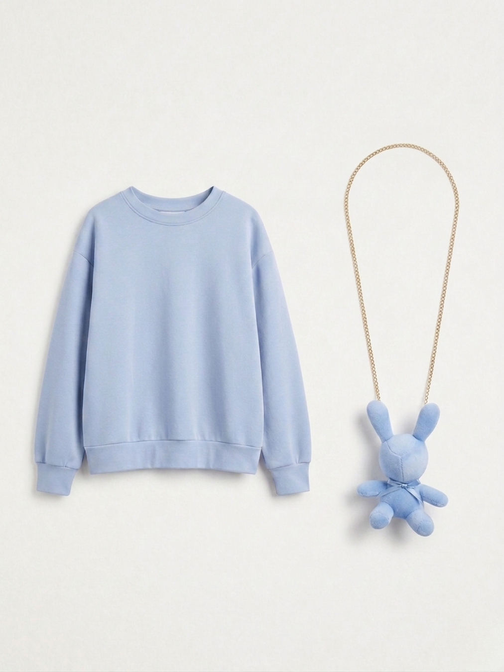 Imagen de producto de la sudadera azul y el collar de conejo presentados en plano.