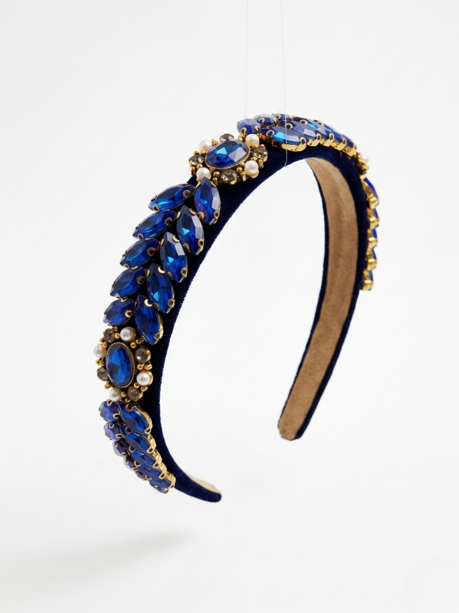 Diadema acolchada de terciopelo azul real con cristales en forma de hoja color zafiro y perlas blancas de Angel Salvaje.
