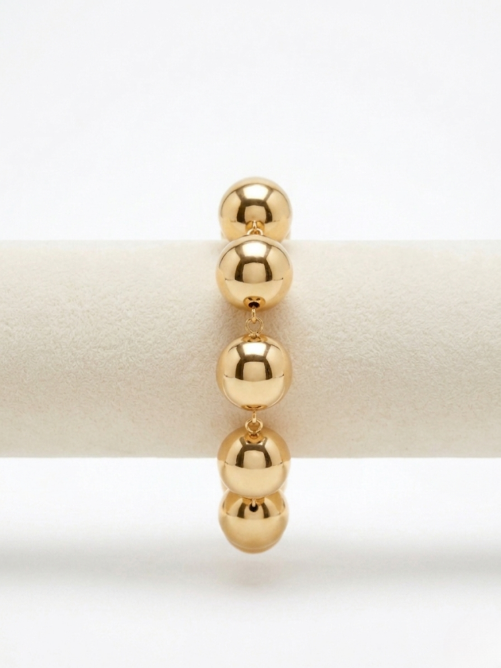 Primer plano de brazalete dorado de cuentas esféricas de volumen grande con acabado pulido reflectante de Angel Salvaje.