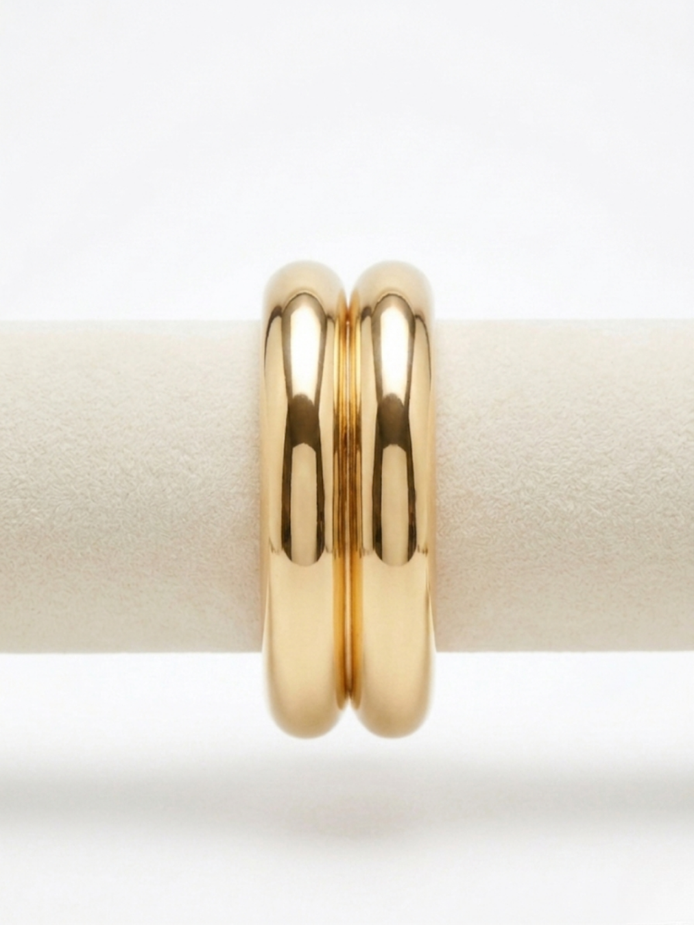 Primer plano de brazalete rígido dorado de diseño doble tubular con acabado pulido brillante de efecto espejo de Angel Salvaje.