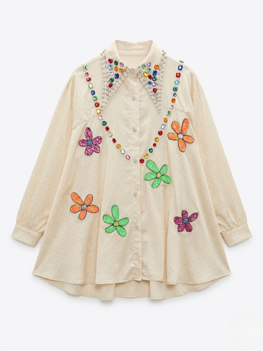 Vista frontal de camisa joya satinada color vainilla con flores de lentejuelas multicolores y pedrería en el cuello.