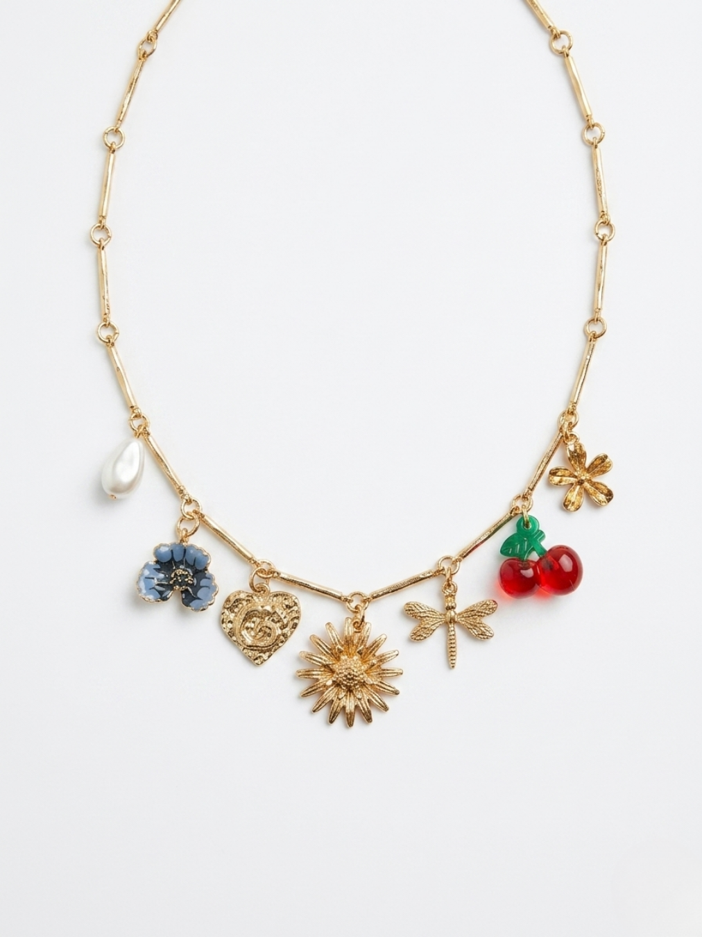 Vista frontal de collar gargantilla dorado con múltiples amuletos colgantes de libélula, sol, flores, corazón y cerezas esmaltadas de Angel Salvaje.