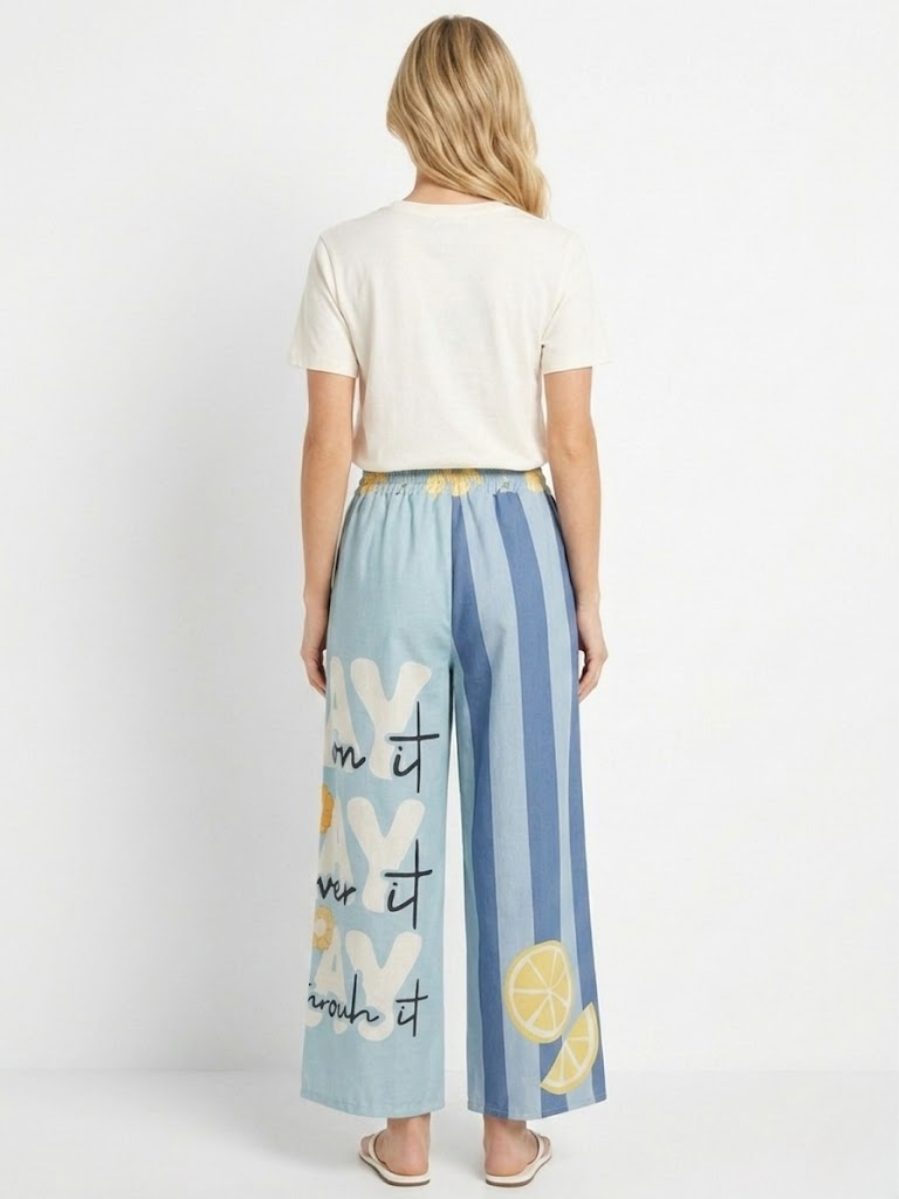 Vista posterior del conjunto en modelo donde se aprecia la caída del pantalón y el diseño de rayas traseras.