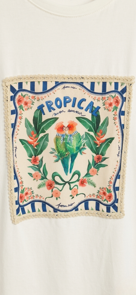 Primer plano del parche central de la camiseta con dos loros, flores tropicales y acabado de crochet.