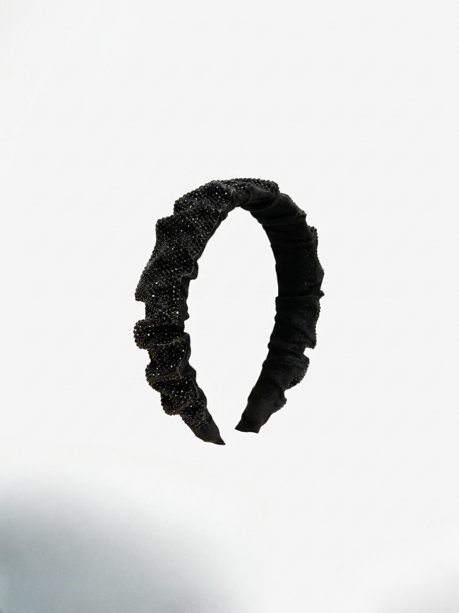 Accesorio para el pelo plisado en color negro con efecto centelleante sutil.