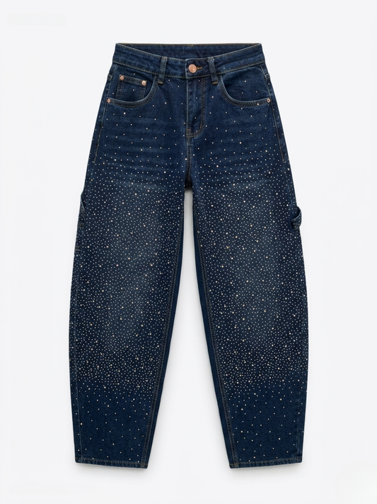 Vaquero azul índigo corte barrel con strass concentrado en las rodillas y seis bolsillos.