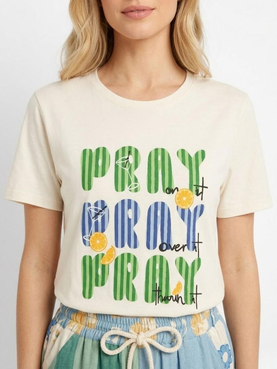 Primer plano de la modelo luciendo la camiseta con el estampado "Pray" y detalles cítricos.