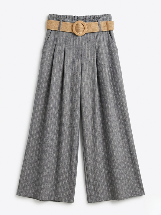 Pantalón fluido gris con rayas blancas finas, bolsillos delanteros y cinturón redondo de rafia.