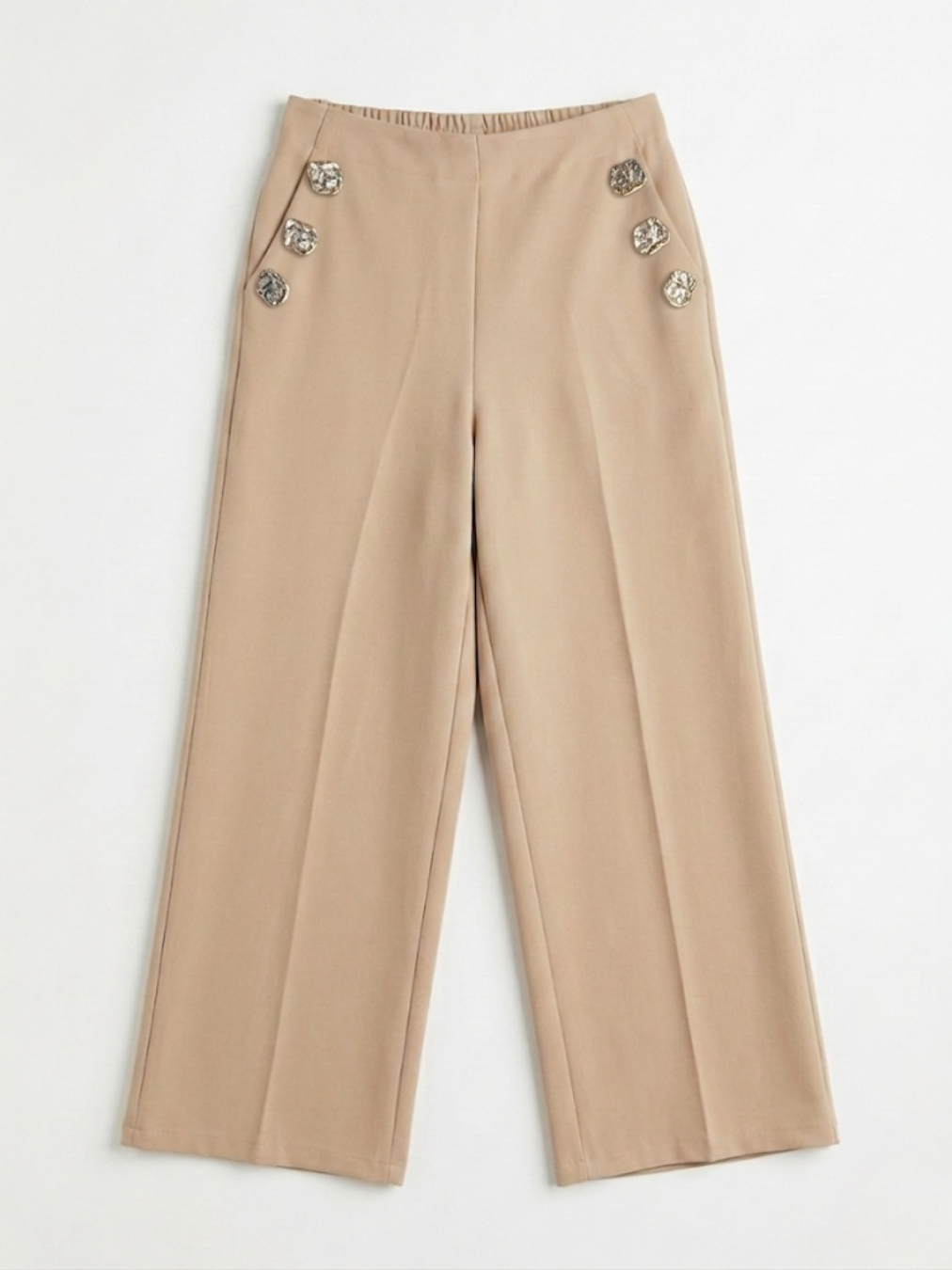 Vista frontal de pantalón fluido color beige de pernera ancha con botones metálicos laterales y bolsillos de Ángel Salvaje.