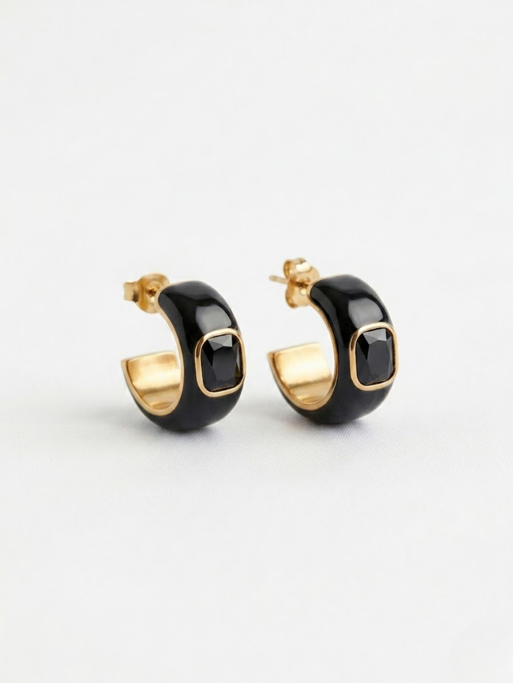 Pendientes de aro negros con cristal negro rectangular y acabado dorado.