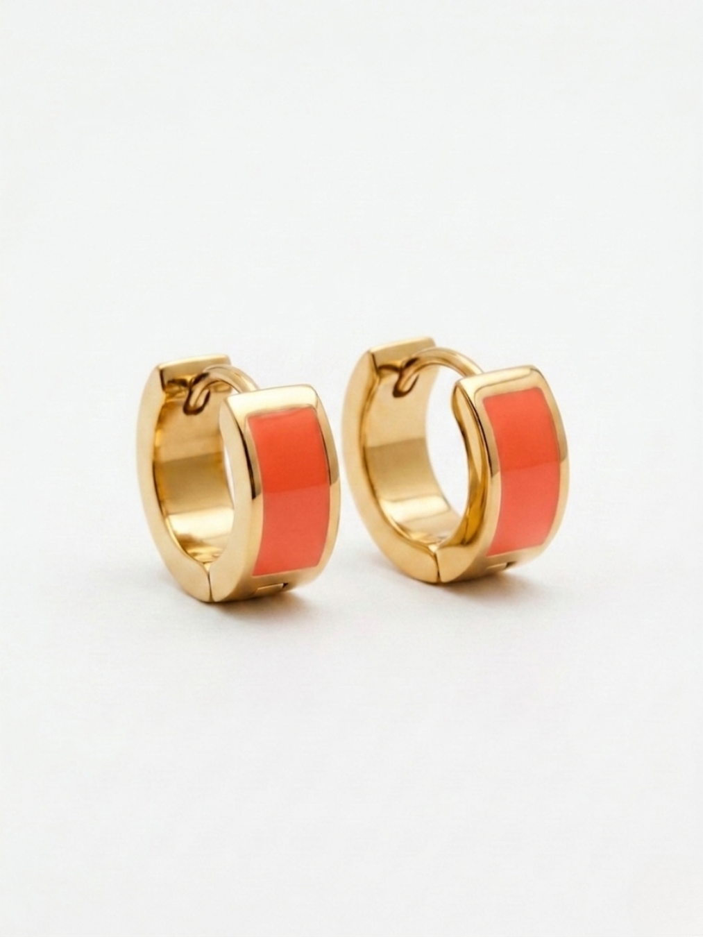 Aros pequeños dorados con banda central esmaltada en color coral.