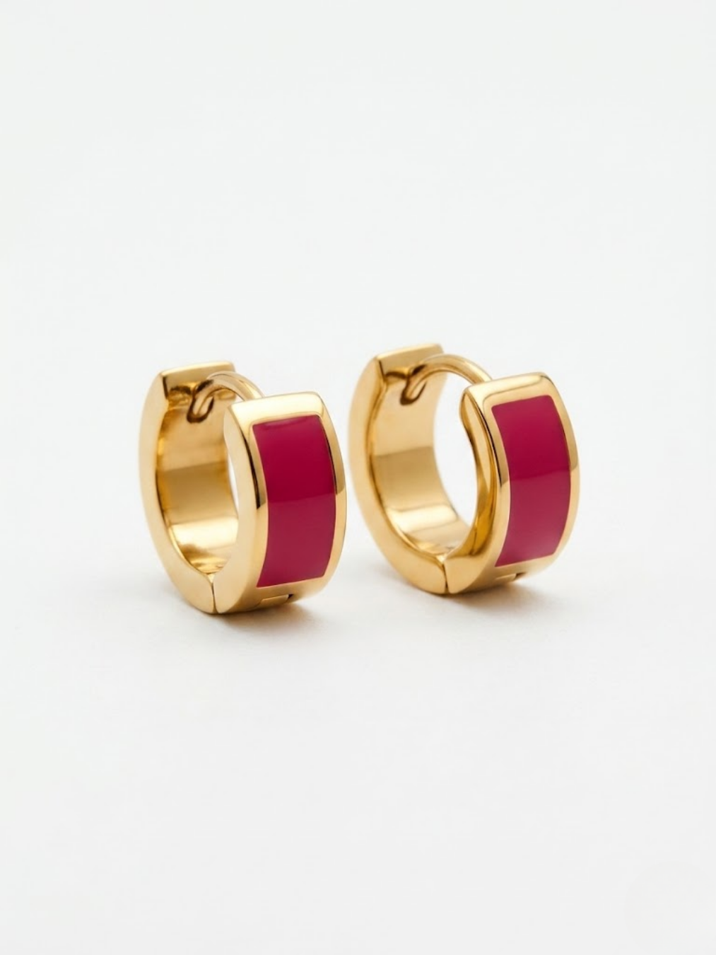 Pendientes aro huggie dorados con detalle de esmalte color frambuesa vibrante.