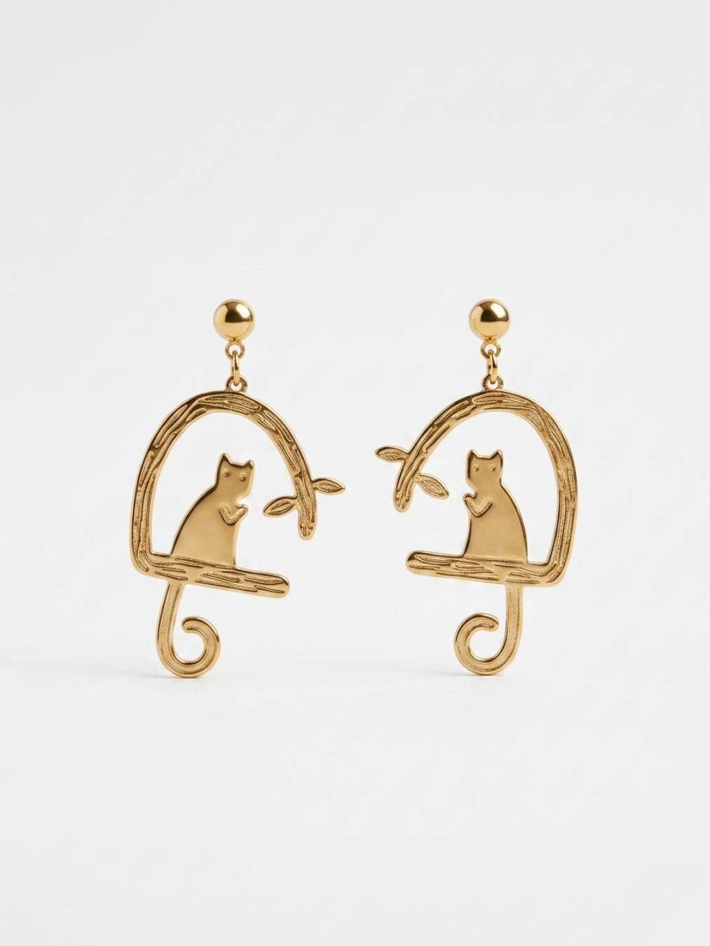 Pendientes dorados con silueta de gato y rama de diseño artístico de la tienda Angel Salvaje.