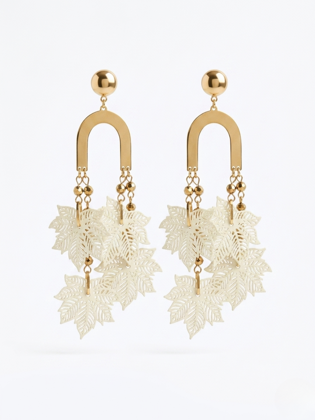 Detalle de pendientes colgantes elegantes con acabado dorado pulido y ramillete de hojas caladas en color marfil o crema.