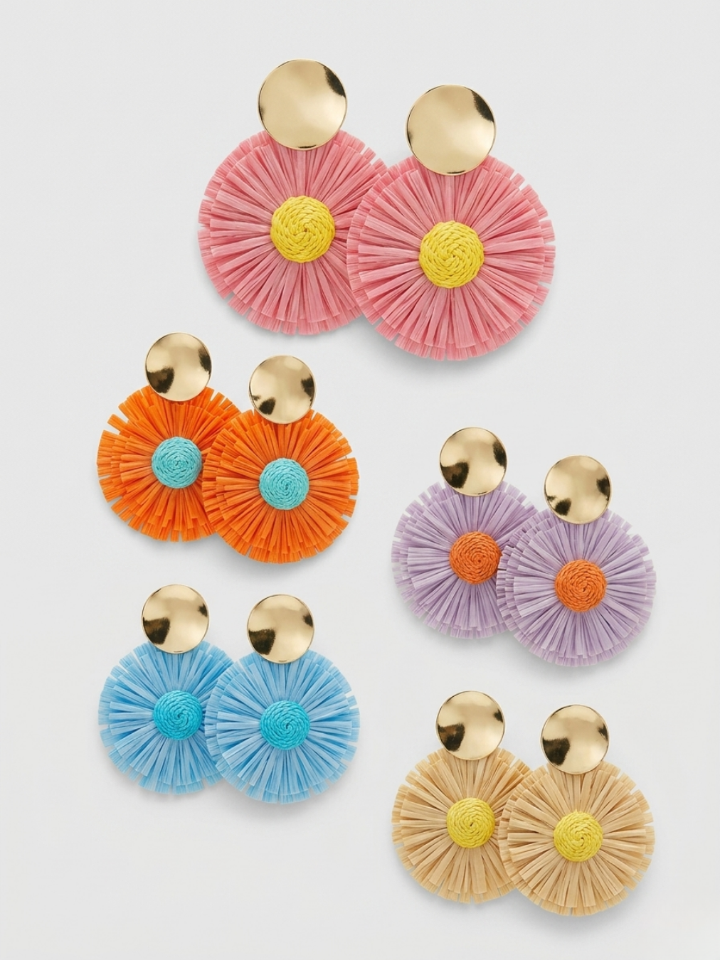 Colección de las cinco variantes de pendientes maxi circulares con base dorada y textura de flecos en abanico en colores rosa pastel, naranja, lavanda, azul celeste y tono paja de Angel Salvaje.