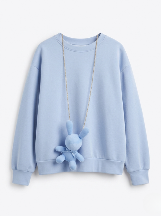 Sudadera azul claro de cuello redondo con accesorio de collar largo y peluche de conejo azul a juego.