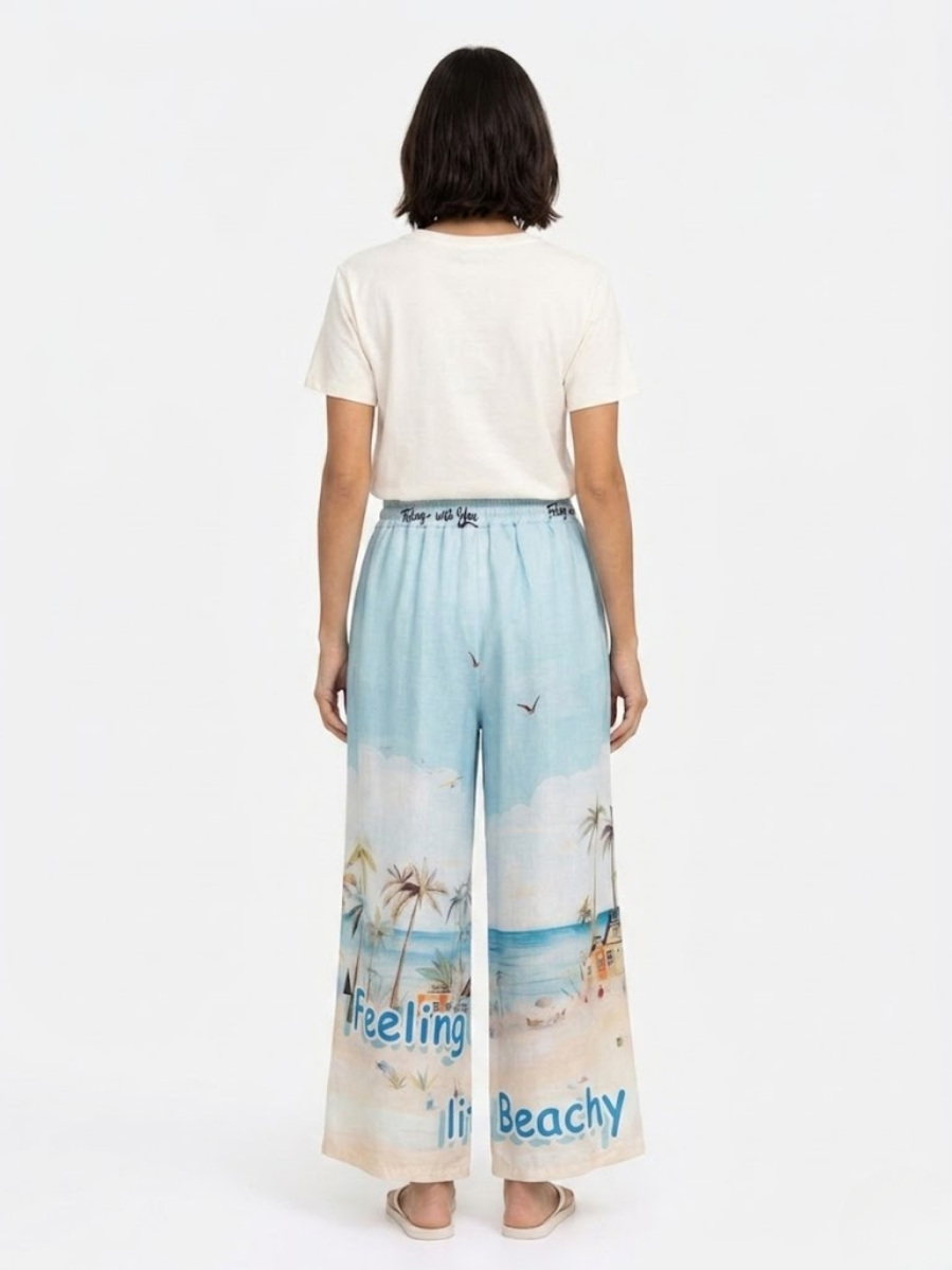 Vista trasera del conjunto en modelo mostrando la caída del pantalón de lino y el diseño de la playa.
